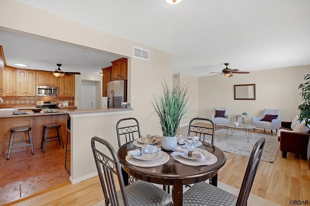 dining space with ceiling fan and light hardwood / wood-style flooring