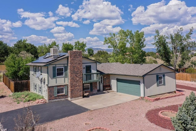 view of front of property featuring a garage, a mountain view, cooling unit, and solar panels