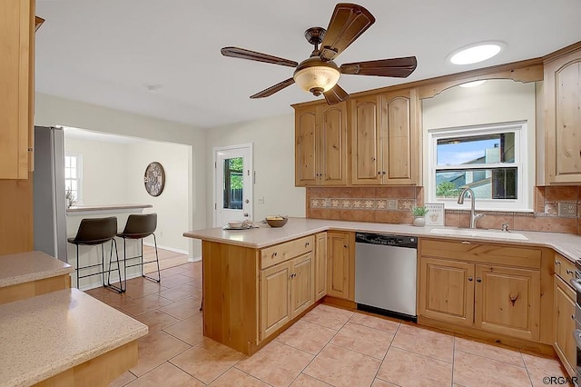 kitchen with dishwasher, sink, kitchen peninsula, and a wealth of natural light