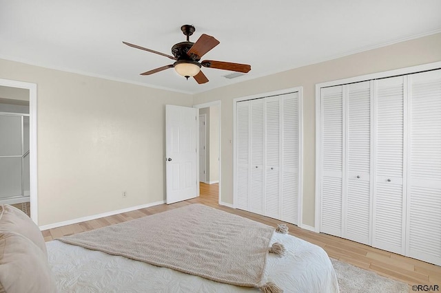 bedroom with multiple closets, wood-type flooring, and ceiling fan