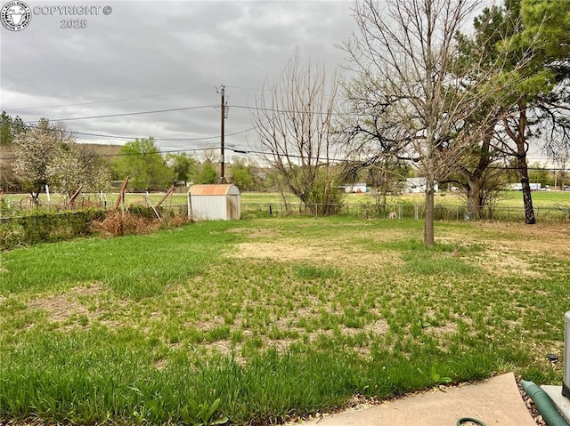 view of yard with an outbuilding, fence, and a storage shed