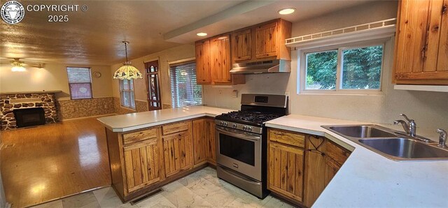 1540 Lombard St, Canon City, CO 81212 - kitchen with stainless steel gas range oven, under cabinet range hood, a peninsula, ceiling fan, and brown cabinetry