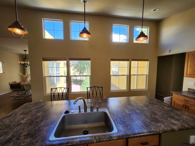 kitchen featuring hanging light fixtures, sink, and a towering ceiling