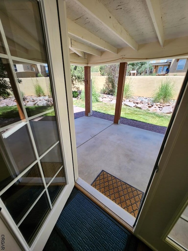 doorway to outside with concrete floors and beam ceiling