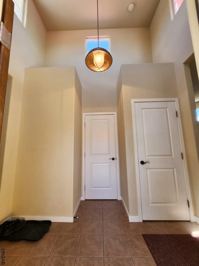 hallway with a towering ceiling and dark tile patterned flooring