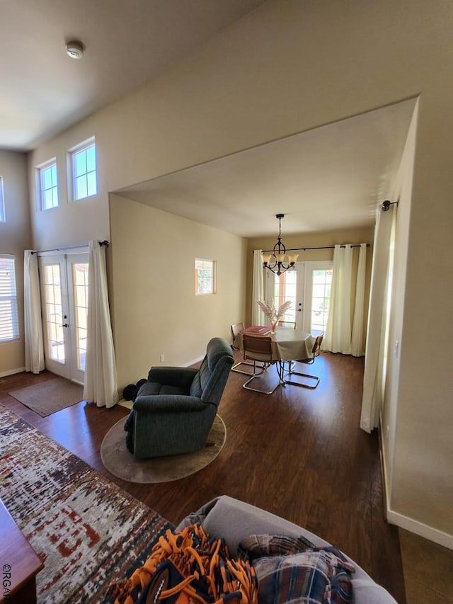 living room with an inviting chandelier, dark wood-type flooring, and french doors