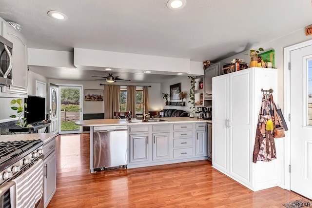 kitchen with light hardwood / wood-style flooring, gray cabinets, ceiling fan, appliances with stainless steel finishes, and kitchen peninsula