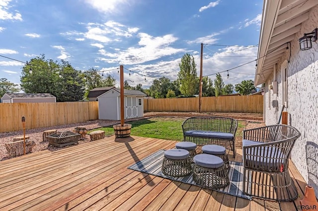 wooden deck featuring a storage shed and a fire pit