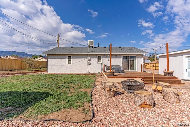 back of house with central AC unit, a fire pit, a lawn, and a deck