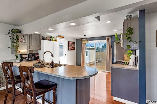 kitchen with gray cabinets, hanging light fixtures, sink, and kitchen peninsula