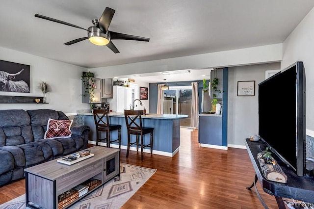 living room with dark hardwood / wood-style flooring, sink, and ceiling fan