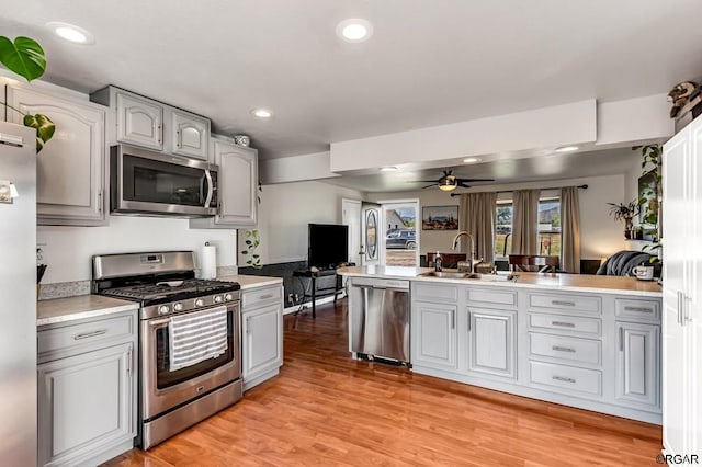 kitchen with sink, gray cabinets, ceiling fan, stainless steel appliances, and light hardwood / wood-style floors