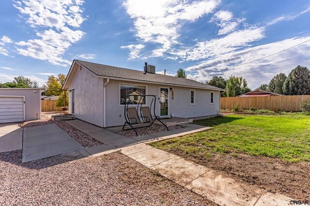 back of house with an outdoor structure and a lawn