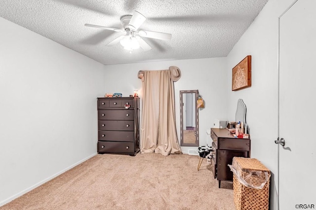 miscellaneous room featuring ceiling fan, light carpet, and a textured ceiling