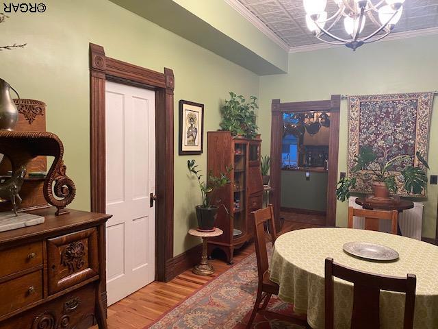 dining space featuring ornamental molding, light hardwood / wood-style flooring, and a notable chandelier