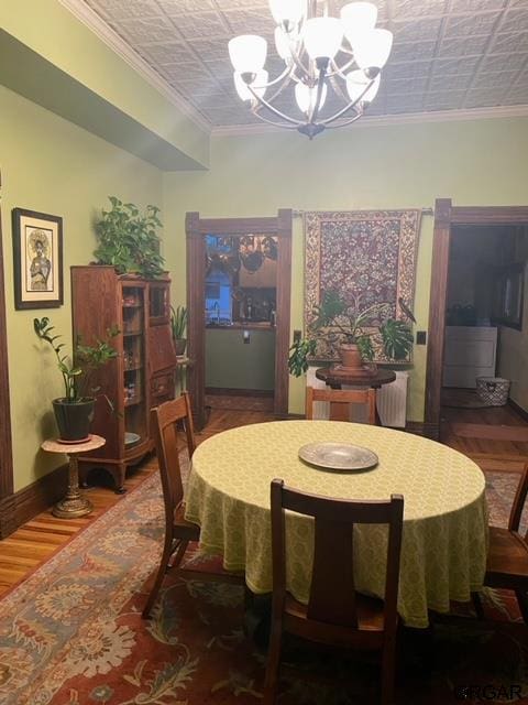 dining room with hardwood / wood-style floors, ornamental molding, and a chandelier