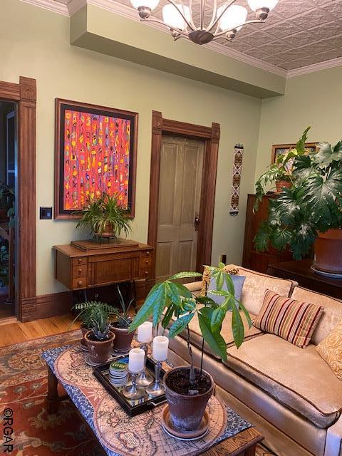 living room featuring a notable chandelier, ornamental molding, and hardwood / wood-style floors