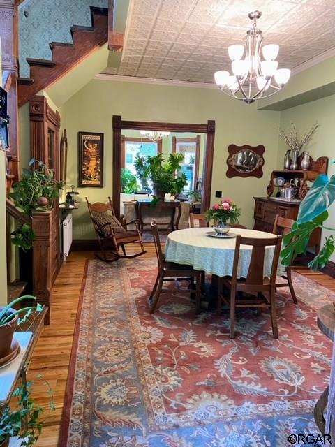 dining space with an inviting chandelier, crown molding, and hardwood / wood-style flooring