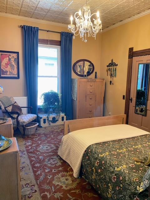 bedroom with ornamental molding and a chandelier