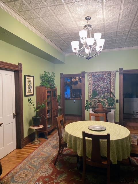 dining room with hardwood / wood-style flooring, crown molding, and a chandelier