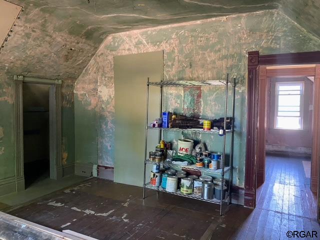 bar with lofted ceiling and wood-type flooring