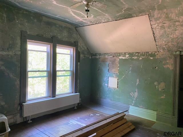 interior space with lofted ceiling, hardwood / wood-style flooring, and radiator heating unit