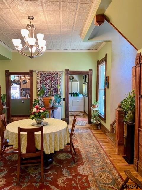 dining space featuring crown molding, an inviting chandelier, and hardwood / wood-style floors