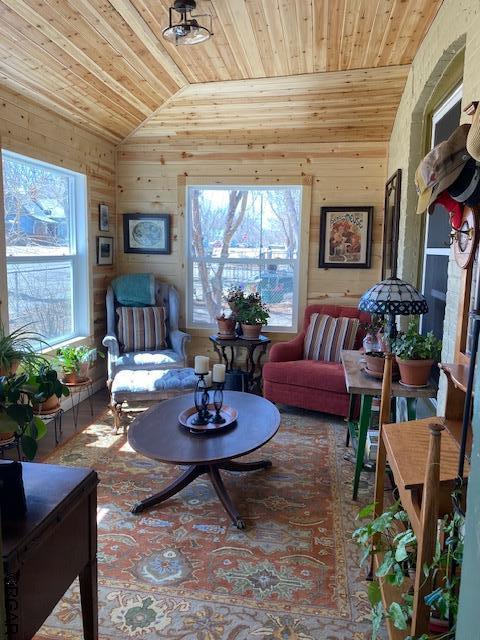 living area featuring wood ceiling, wooden walls, and vaulted ceiling