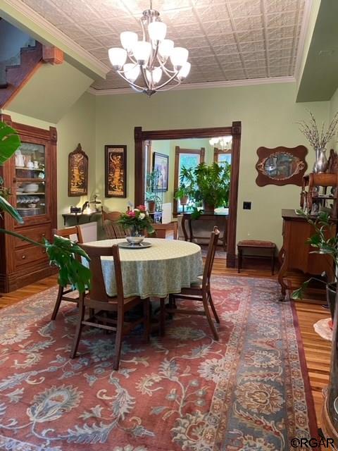 dining area featuring a notable chandelier, crown molding, and hardwood / wood-style flooring