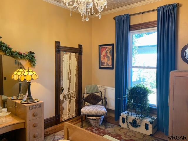 living area with crown molding and a notable chandelier