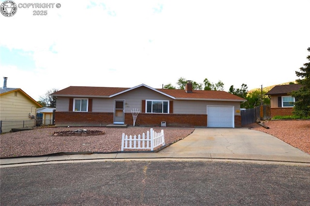 ranch-style home featuring fence private yard, a chimney, brick siding, concrete driveway, and an attached garage