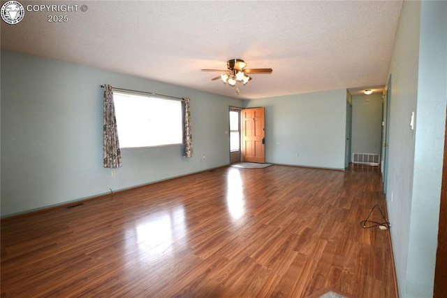 empty room featuring baseboards, ceiling fan, visible vents, and wood finished floors