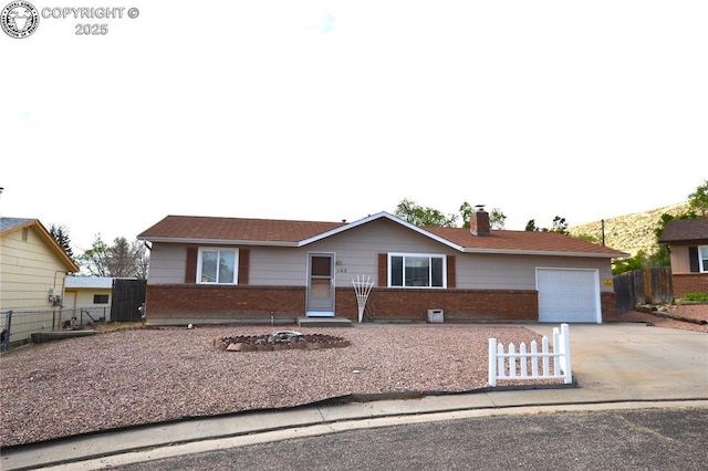 ranch-style house featuring brick siding, driveway, fence, and a garage