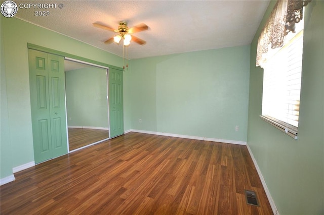 unfurnished bedroom with baseboards, a closet, wood finished floors, and visible vents