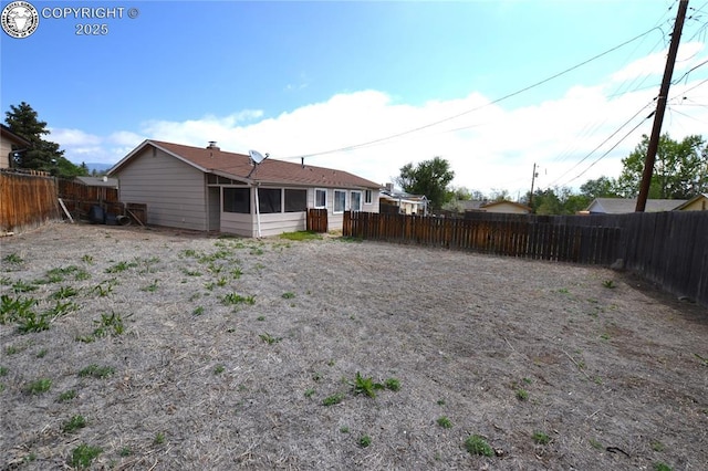 rear view of house with a fenced backyard and a sunroom