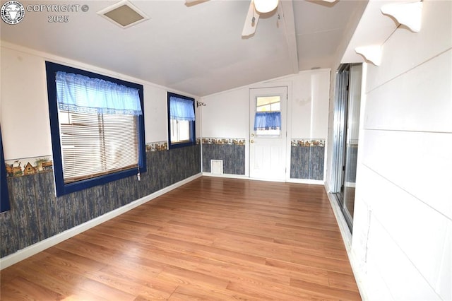 unfurnished room with ceiling fan, vaulted ceiling, wood finished floors, and a wainscoted wall