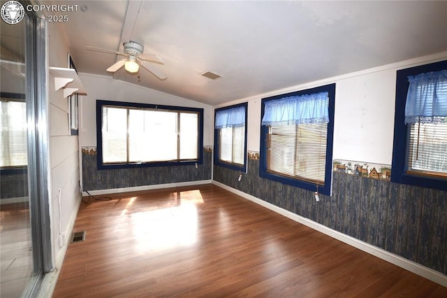 unfurnished room with ceiling fan, vaulted ceiling, wainscoting, and wood finished floors