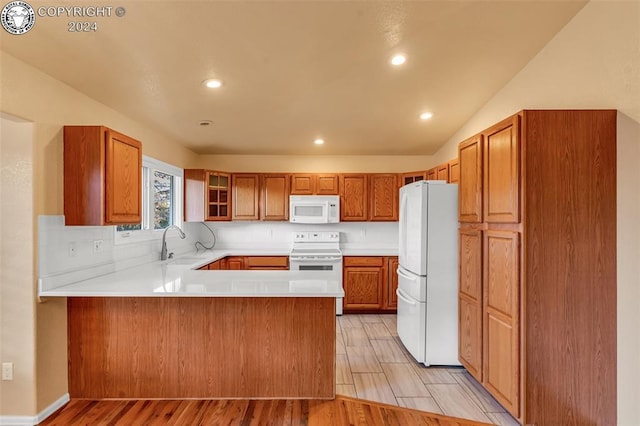 kitchen featuring sink, tasteful backsplash, light hardwood / wood-style flooring, kitchen peninsula, and white appliances