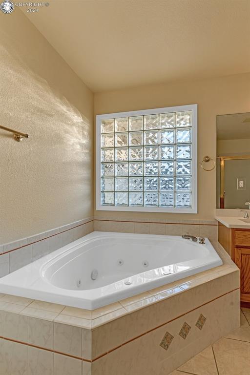 bathroom featuring vanity, tiled tub, and tile patterned floors