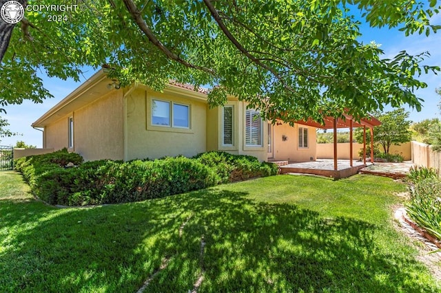 back of property featuring a pergola, a lawn, and a patio area