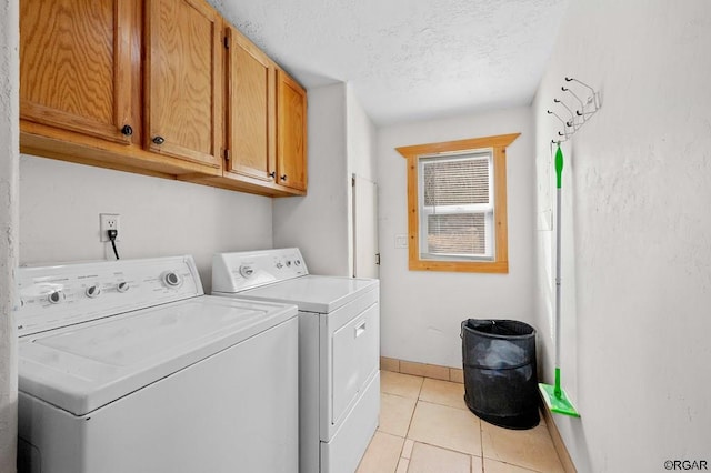 laundry area featuring cabinets, light tile patterned flooring, a textured ceiling, and independent washer and dryer