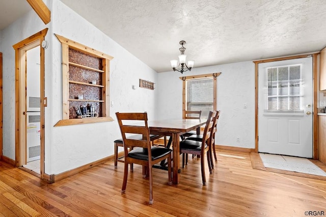 dining room featuring wood-type flooring, a wealth of natural light, an inviting chandelier, and a textured ceiling