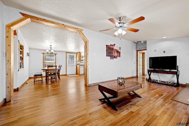 living room featuring ceiling fan, light wood-type flooring, built in features, and a textured ceiling