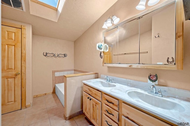 bathroom featuring tile patterned floors, a skylight, vanity, and a tub