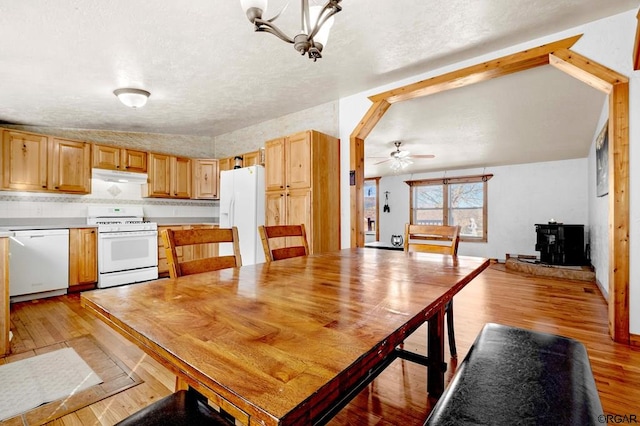 unfurnished dining area featuring lofted ceiling, ceiling fan with notable chandelier, light hardwood / wood-style flooring, and a textured ceiling