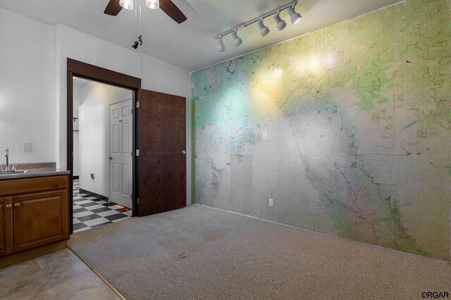 interior space with light colored carpet, track lighting, ceiling fan, and sink