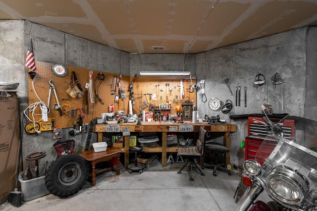 miscellaneous room with concrete flooring and a workshop area