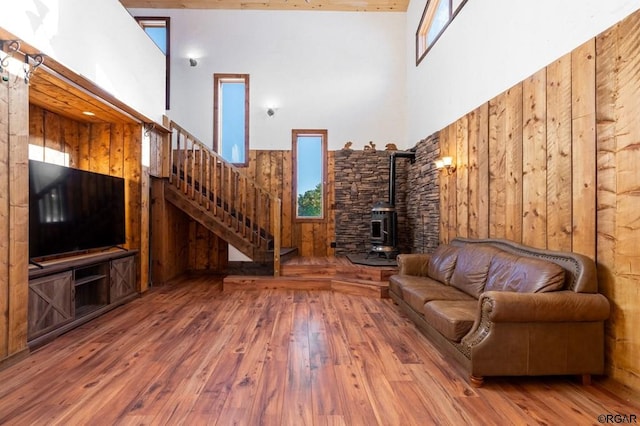 unfurnished living room with hardwood / wood-style flooring, a towering ceiling, and a wood stove