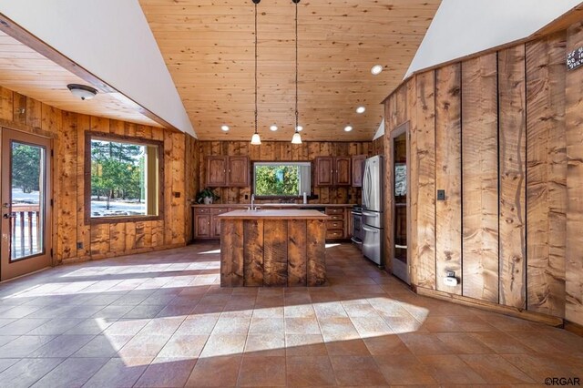 kitchen with wood ceiling, stainless steel fridge, hanging light fixtures, and a kitchen island