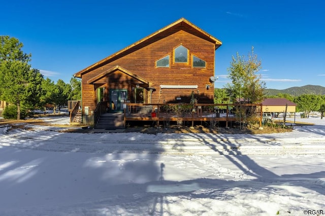 snow covered rear of property featuring a deck with mountain view